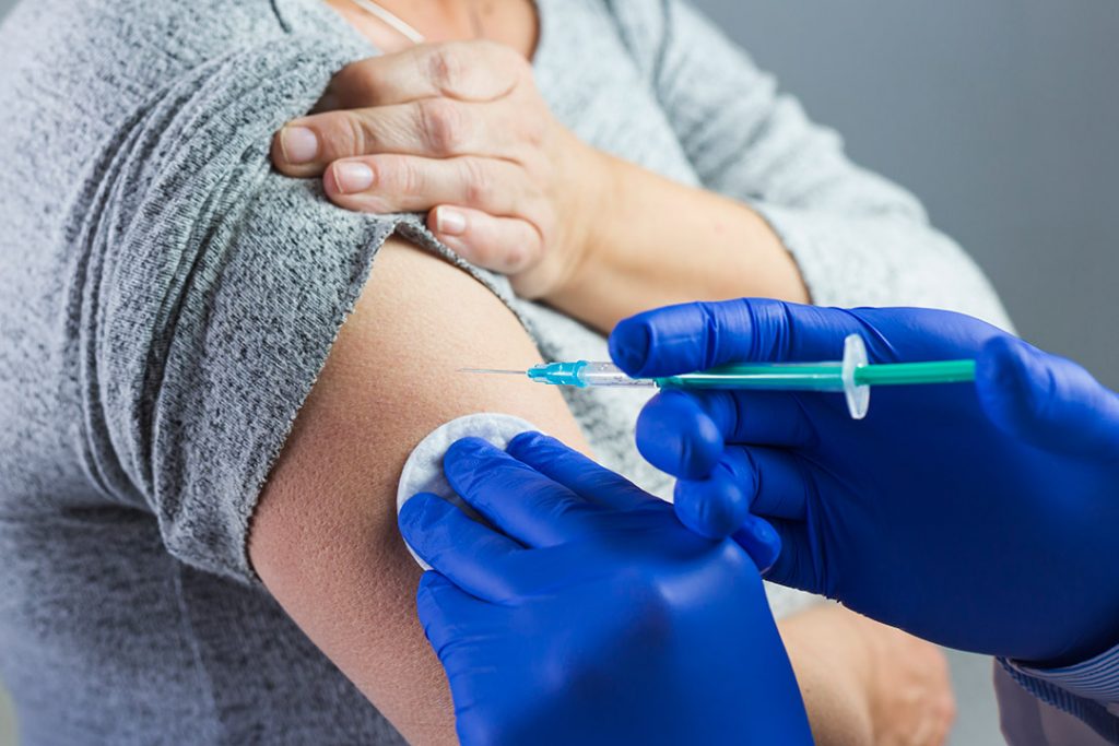 El brazo de un paciente al que un sanitario le está inyectando una vacuna
